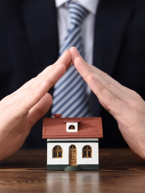 Man in office wear protecting house model. Home insurance