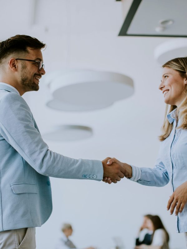 Young business couple handshaking in the office Young business couple handshaking in the office in front of their team
